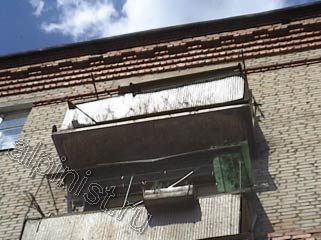 Еще один балкон, который начал рассыпаться, по периметру балконной плиты остался только металлический каркас, нижняя часть плиты сильно разрушена, с боковых частей плиты балкона штукатурка давно отвалилась.