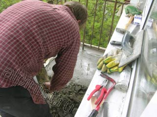Мы подготовили плиту балкона к устройству стяжки, померили уровнем ширину доски для опалубки, установили ее и сейчас наш специалист занимается заливкой стяжки