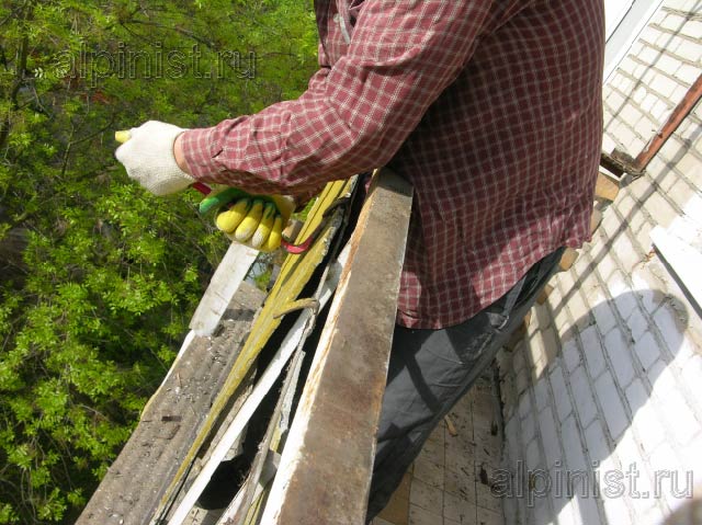 наш специалист отгибает металл, который держит балконные ограждения снаружи балкона