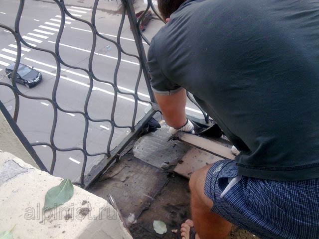 Наш специалист начал проводить демонтаж керамической плитки с пола балкона, на фотографии видно как он убирает плитки с пола.