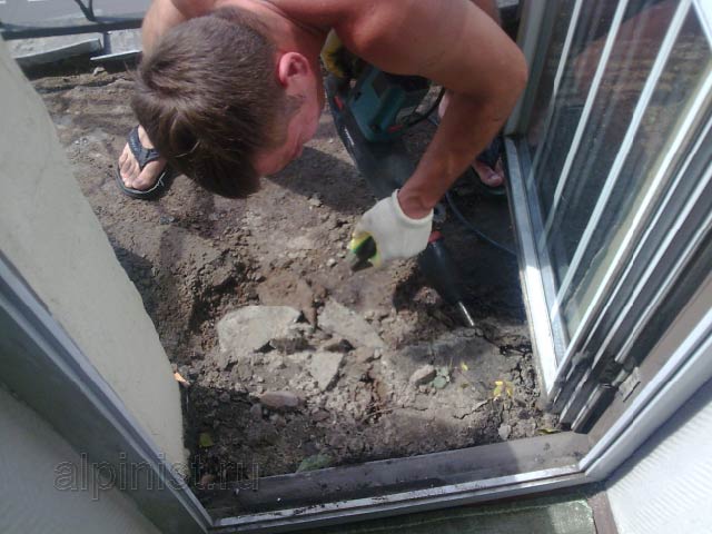 Сначала мы демонтировали керамическую плитку, теперь наш специалист с помощью отбойника отбивает старую стяжку с пола балкона.