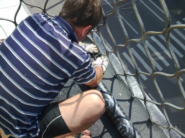 Сейчас наш специалист прорезает небольшие отверстия на кровельном рулонном материале, для того чтобы можно было обойти металлические ограждения балкона и покрыть стяжку полностью.