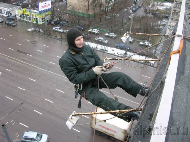 специалист закрепил веревки на крыше, после чего, применяя технику промышленного альпинизма он спустится вниз к месту крепления банера