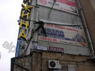 Для того, чтобы  снять репшнур с левой вертикальной стороны баннера, наш альпинист маятником раскачался на веревке и зацепился ногой за угол здания
