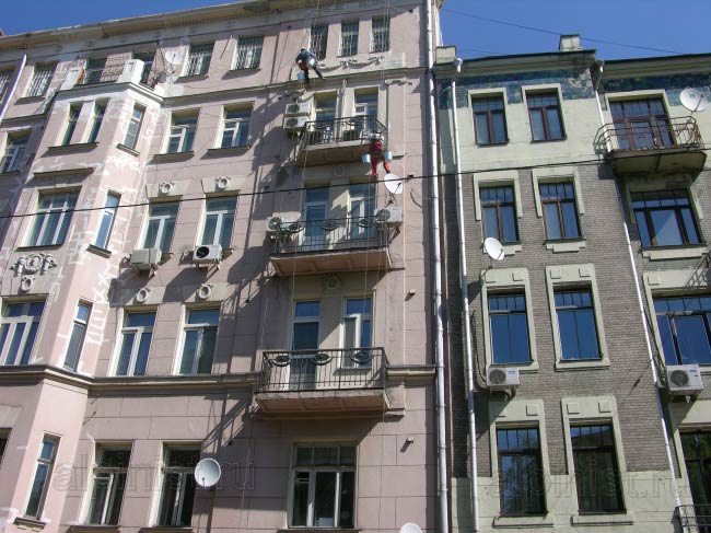 альпинисты расшивают и шпатлюют трещины на фасаде, выравнивают балконные плиты