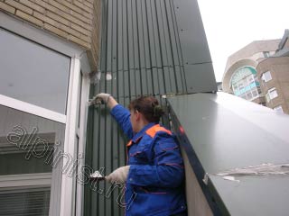 На этой фотографии показано, как наш специалист промазывает специальным герметиком примыкания металлического листа к стене.