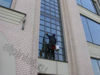 На этой фотографии показан наш альпинист, который, используя специальное снаряжение и технику промышленного альпинизма, моет оконный пролет с небольшими окнами с фасадной стороны.