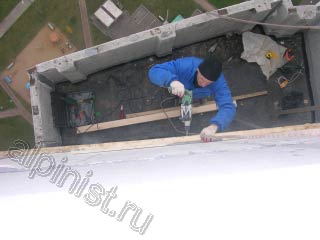 Для выполнения высотных работ по устройству крыши над балконом, наш специалист применяет дрель, которой сейчас высверливает отверстия для саморезов, которые крепят обрешетку кровли