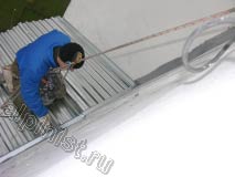 Применяя технику промышленного альпинизма, наш специалист спустился вниз на установленную крышу балкона и сейчас герметизирует примыкания между листами профнастила кровли и примыкания к стене