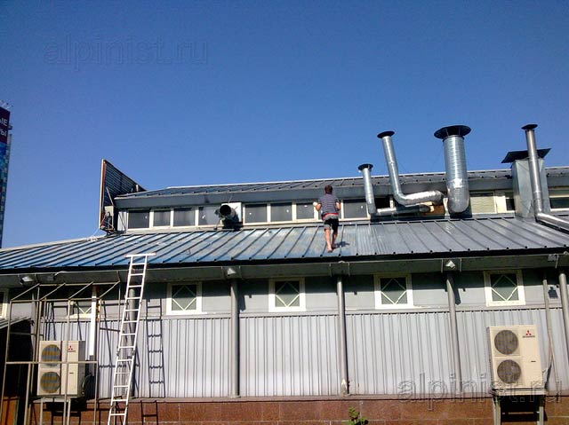 На фотографии видно нашего мастера, который в данное время проводит работы по покраске поверхности крыши.