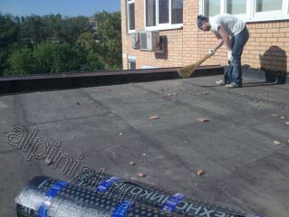 На предоставленной фотографии показан наш кровельщик, который в настоящее время готовит поверхность крыши к ремонту, а именно подметает мусор очищая поверхность.
