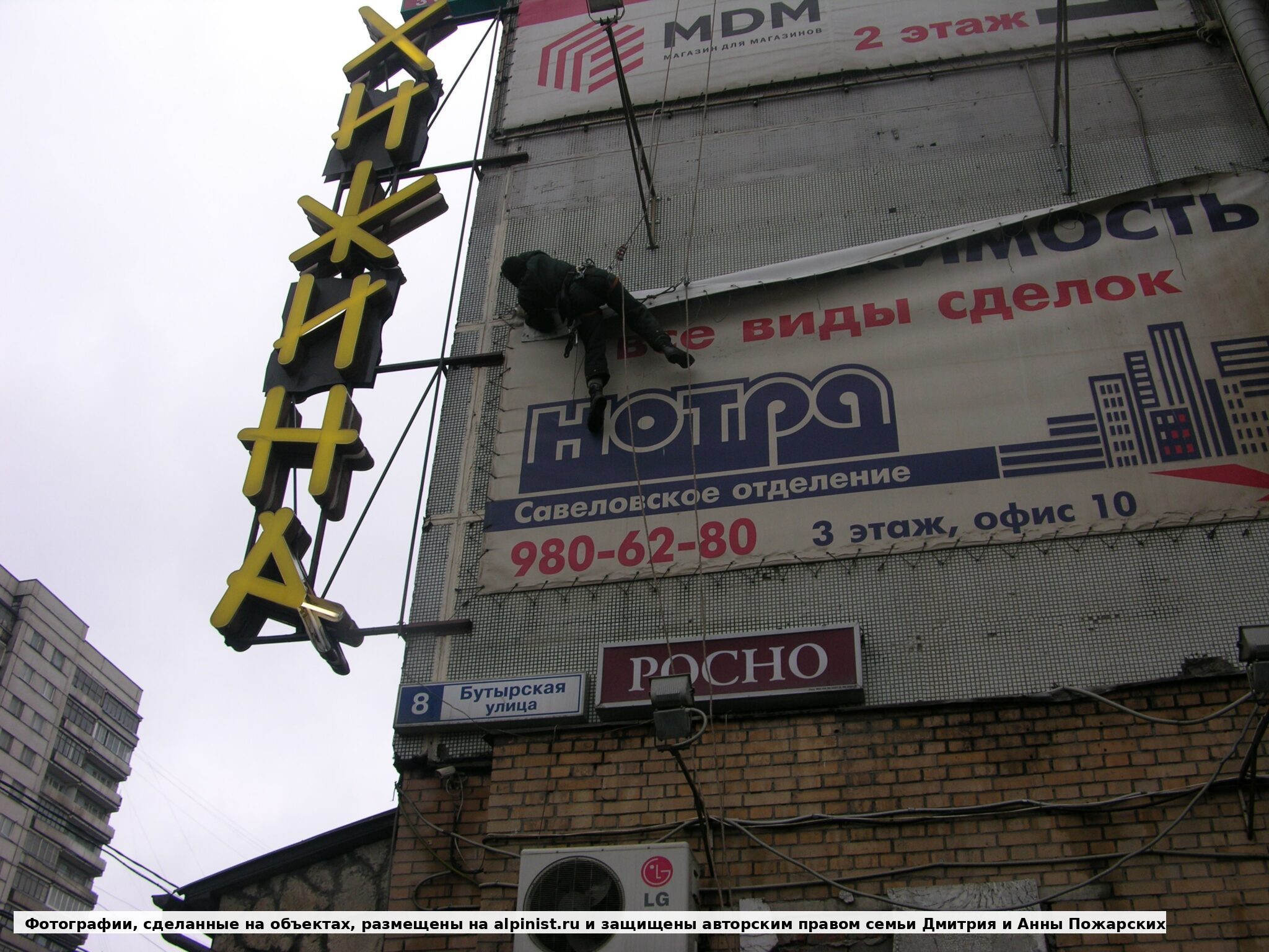 Работа у верхней части рекламного баннера рядом с фонарями фасада