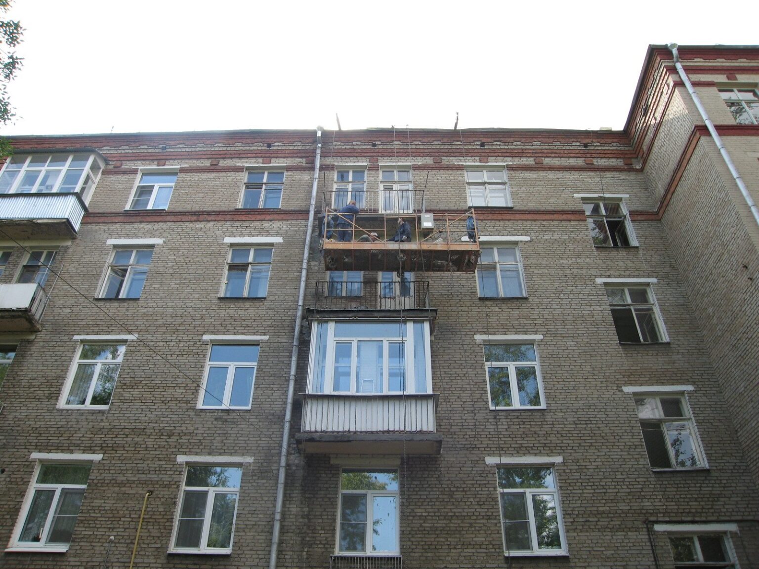 Строительная люлька у балконных плит пятиэтажного дома на Банном переулке во время ремонта