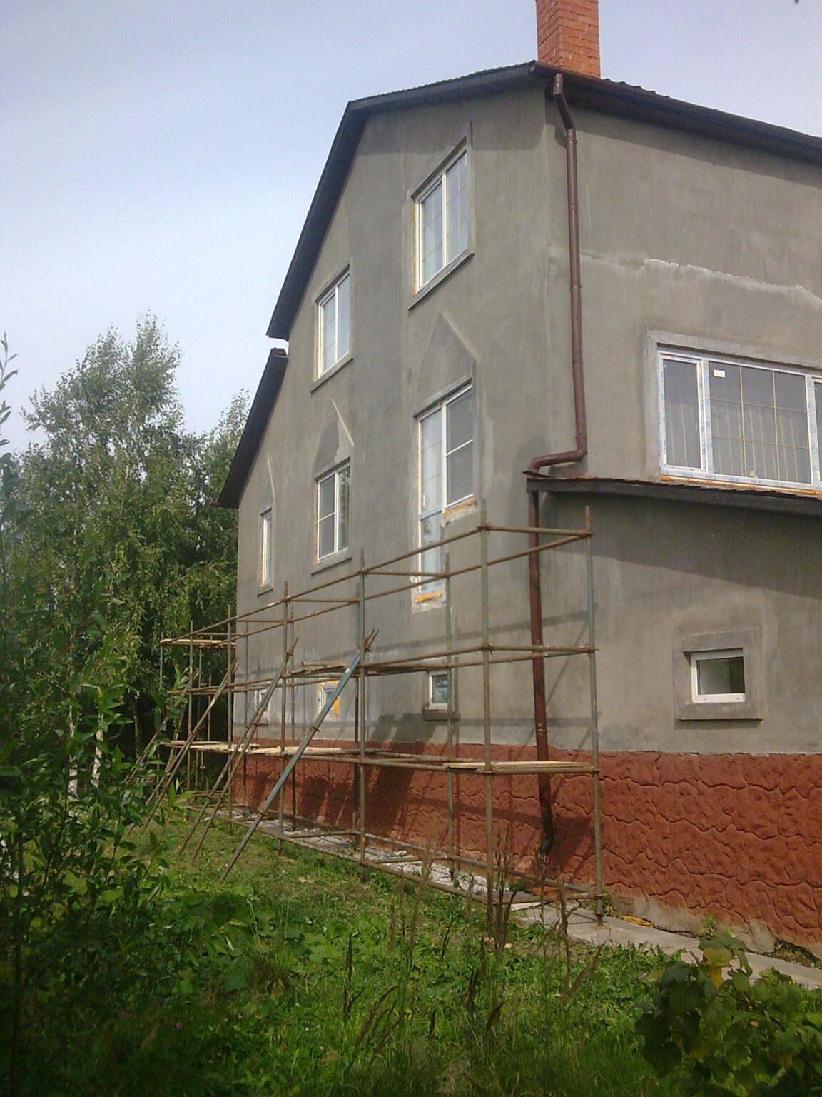 Серый фасад загородного дома на Пятницком шоссе до утепления, рядом установлены строительные леса