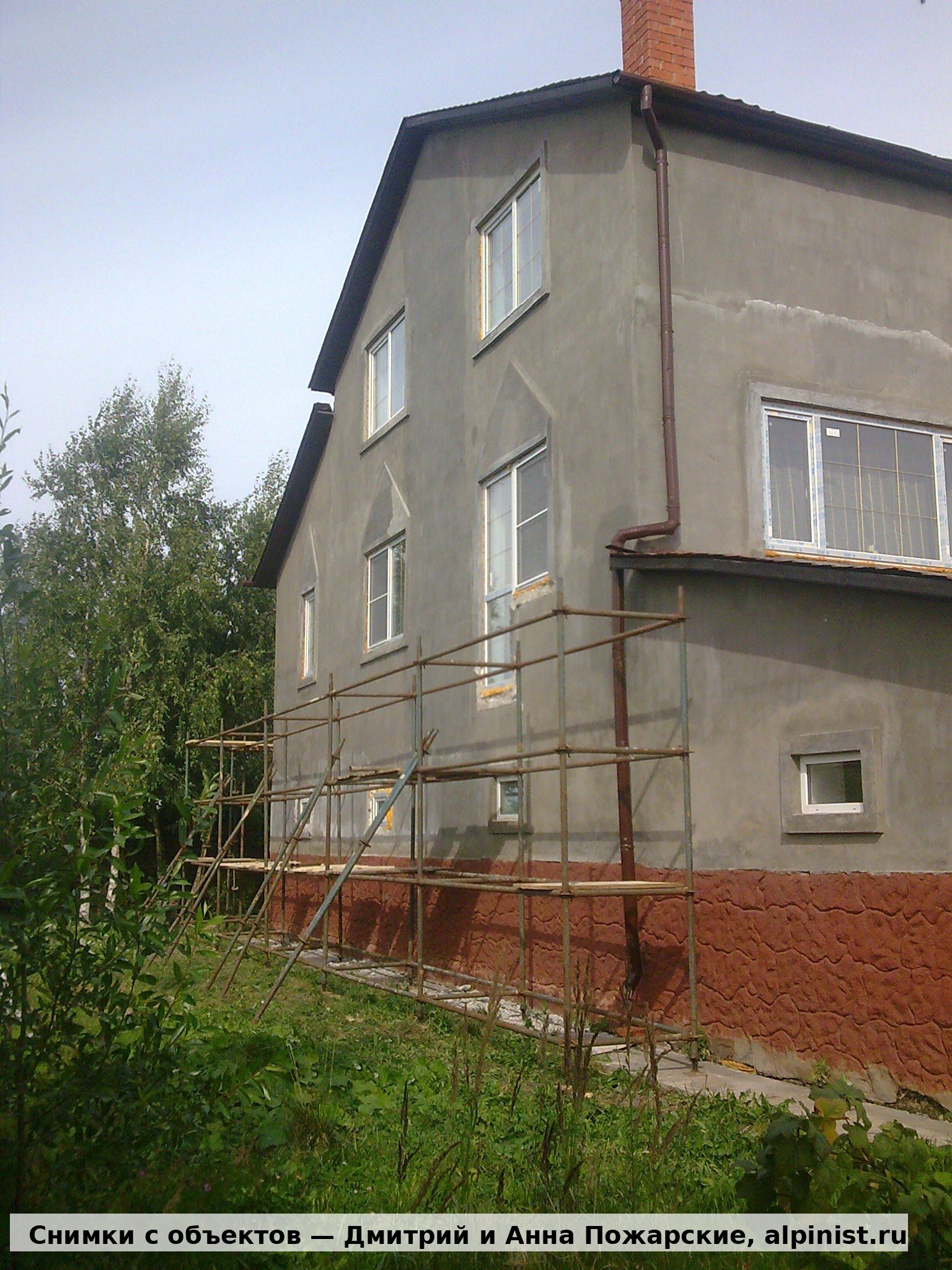 Серый фасад загородного дома на Пятницком шоссе до утепления, рядом установлены строительные леса